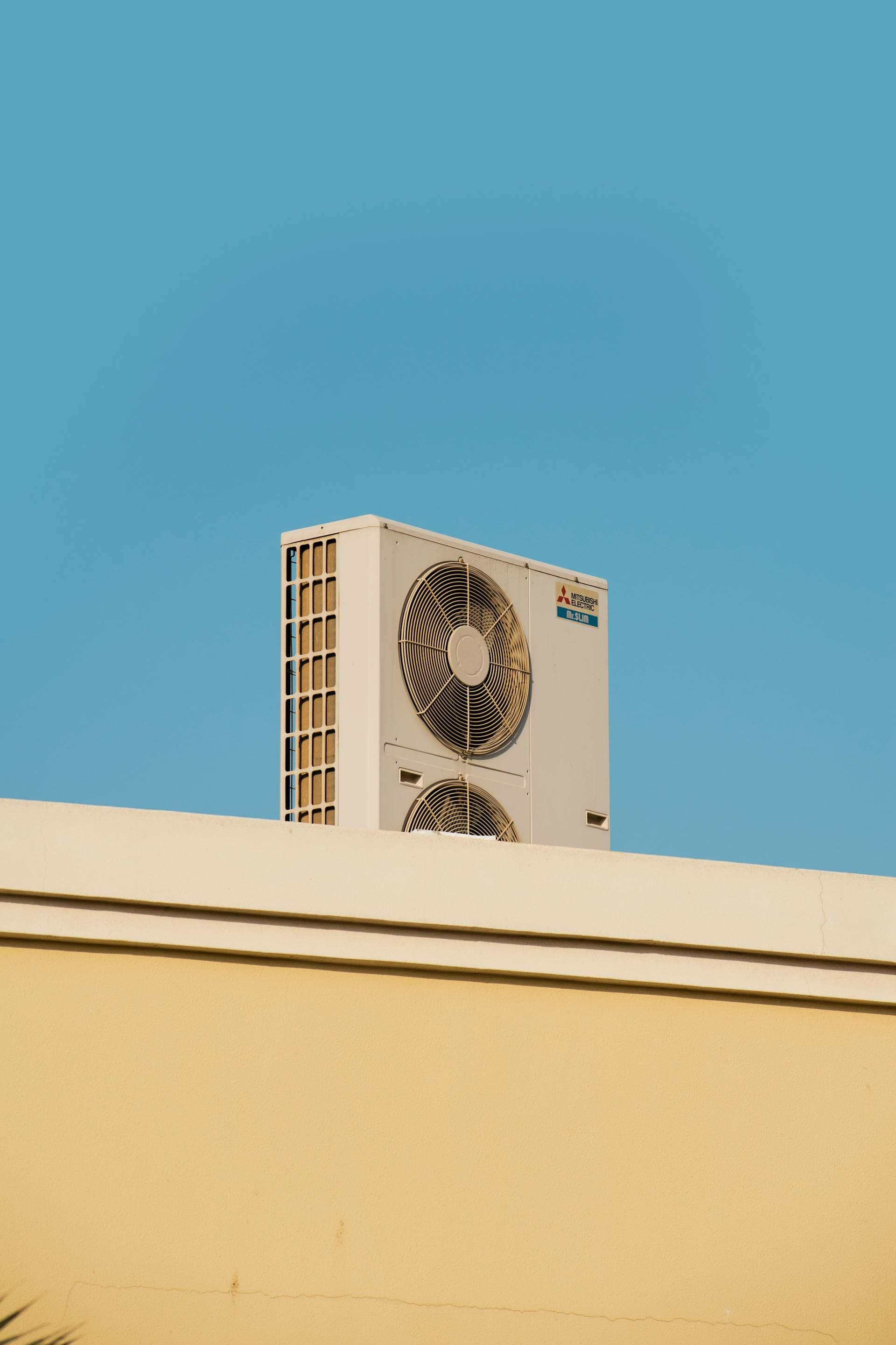 Modern air conditioning condenser unit on rooftop against blue sky