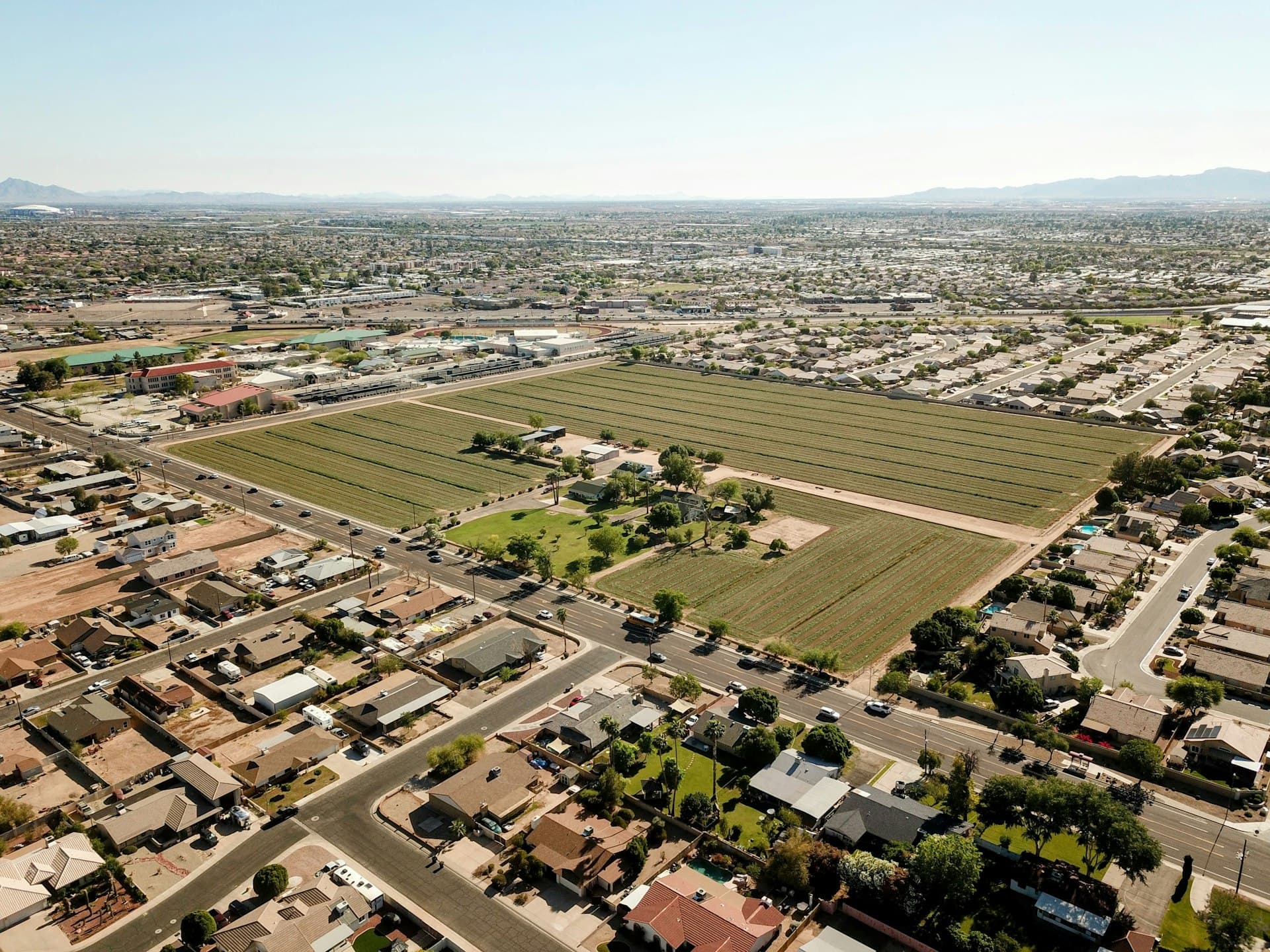 Aerial view of Phoenix metro suburban development with agricultural land and residential neighborhoods