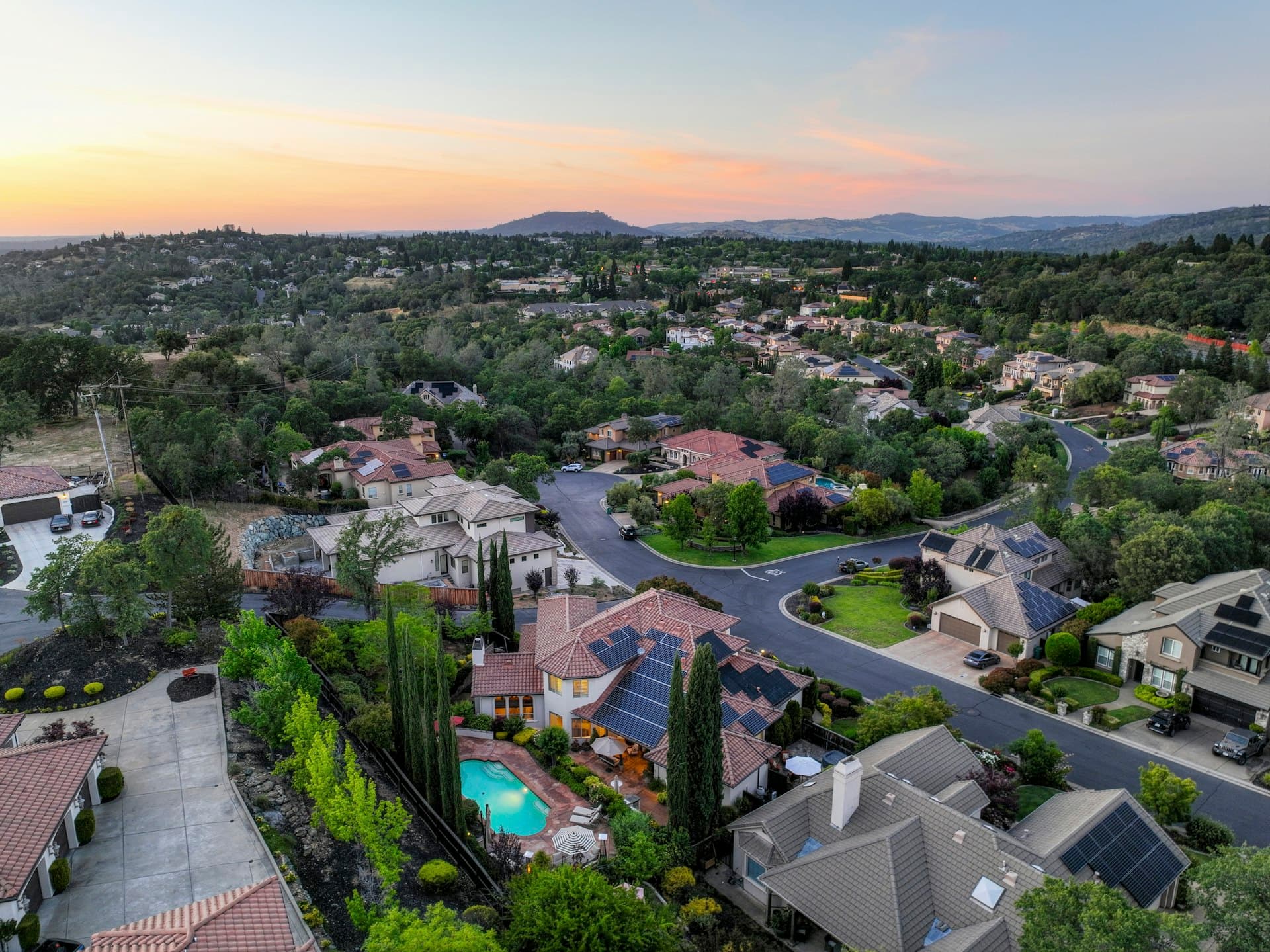 Aerial view of Southern California suburban neighborhood with tile roofs and solar panels at sunset