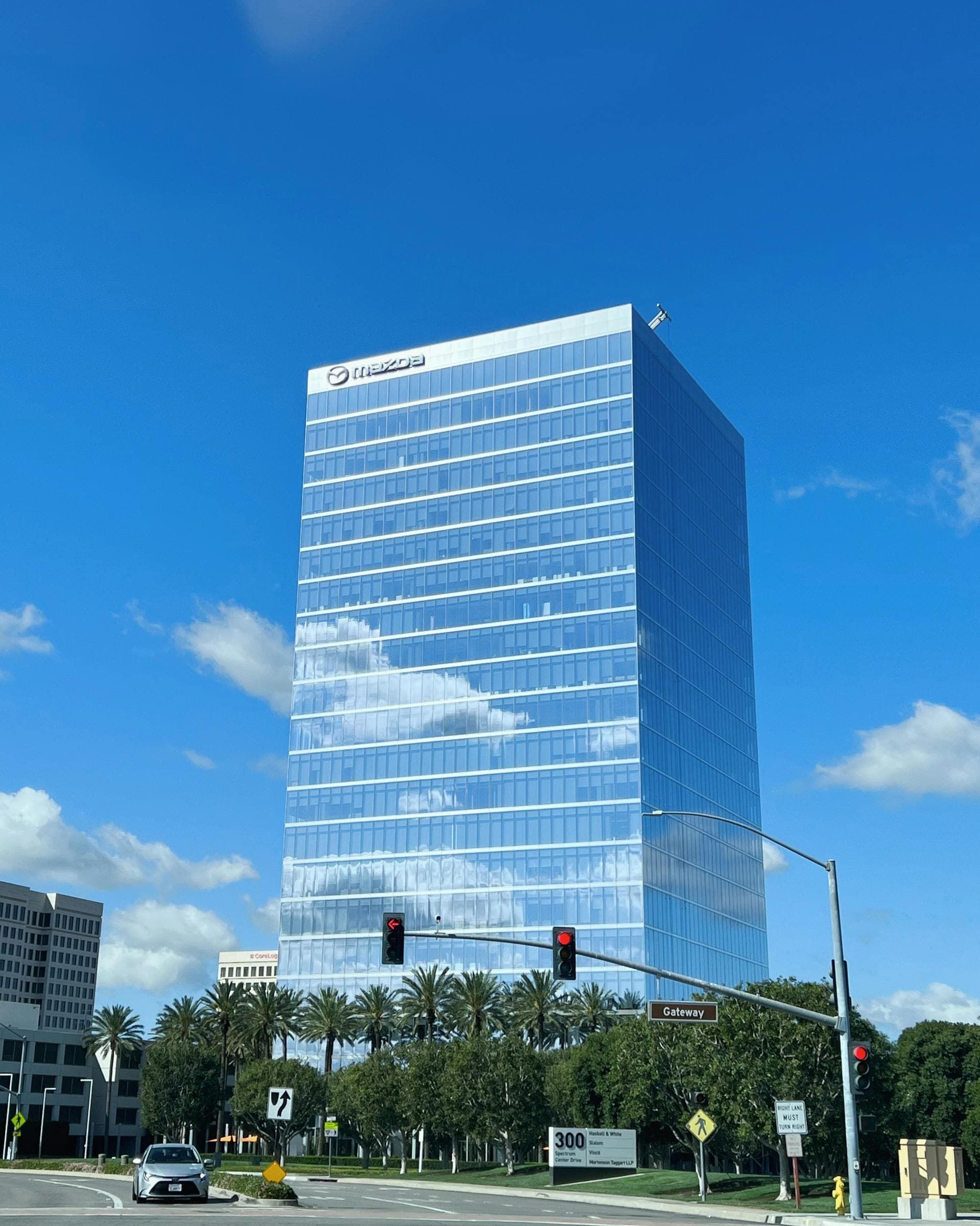 Mazda headquarters skyscraper in Irvine California with palm trees and blue sky