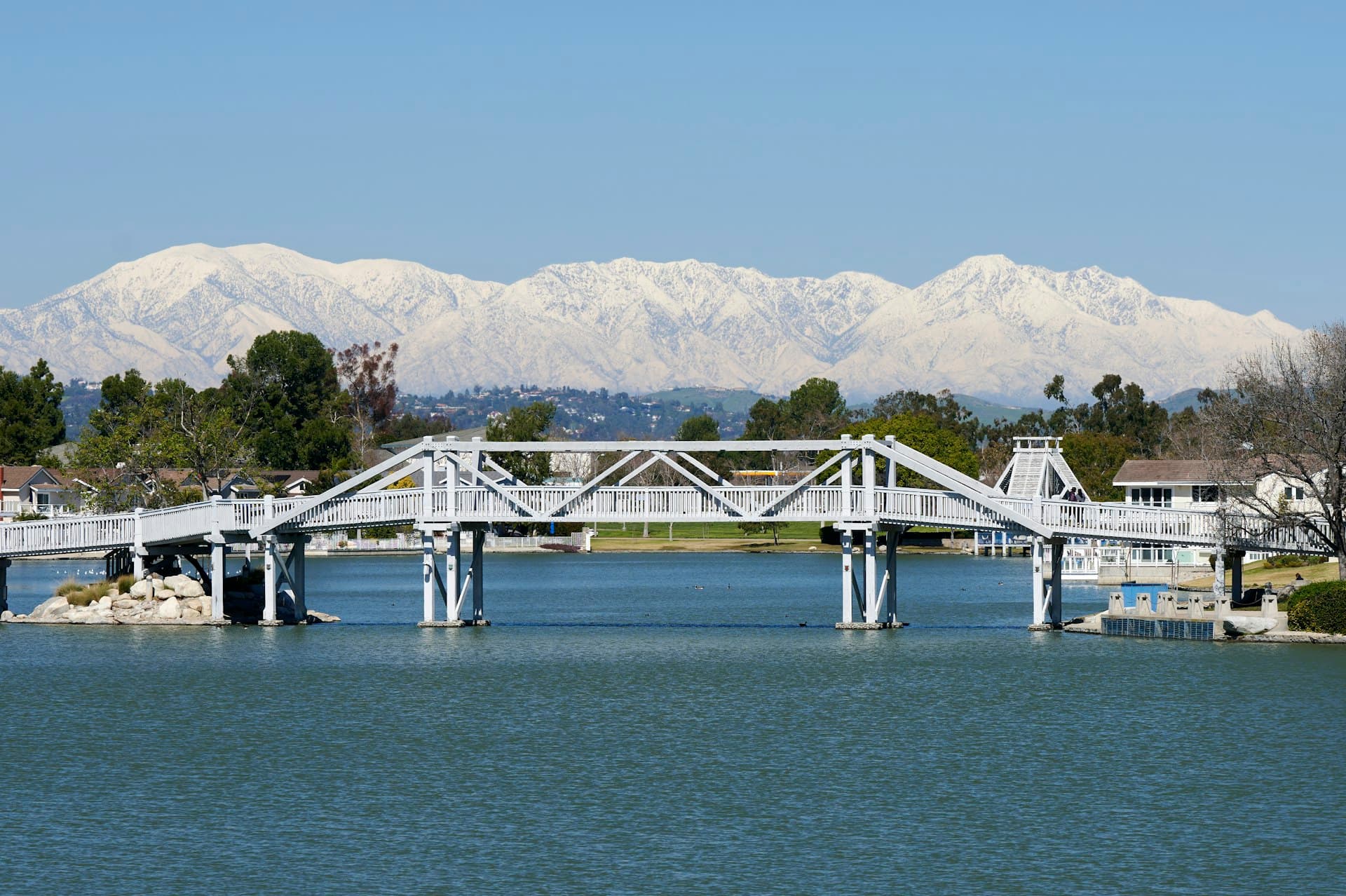 Bridge over South Lake in Woodbridge Irvine with snow-capped mountains in background
