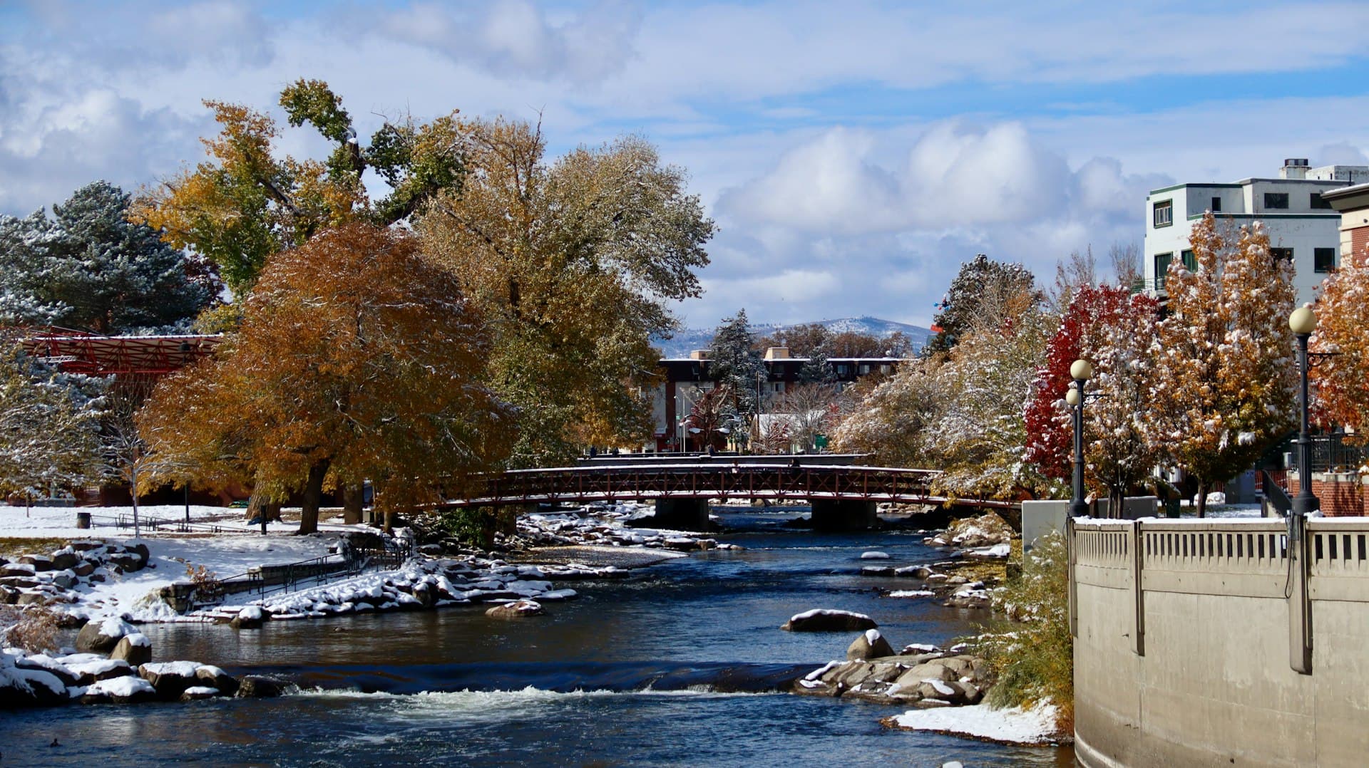 Truckee River Walk in Reno with bridge and fall foliage dusted with snow