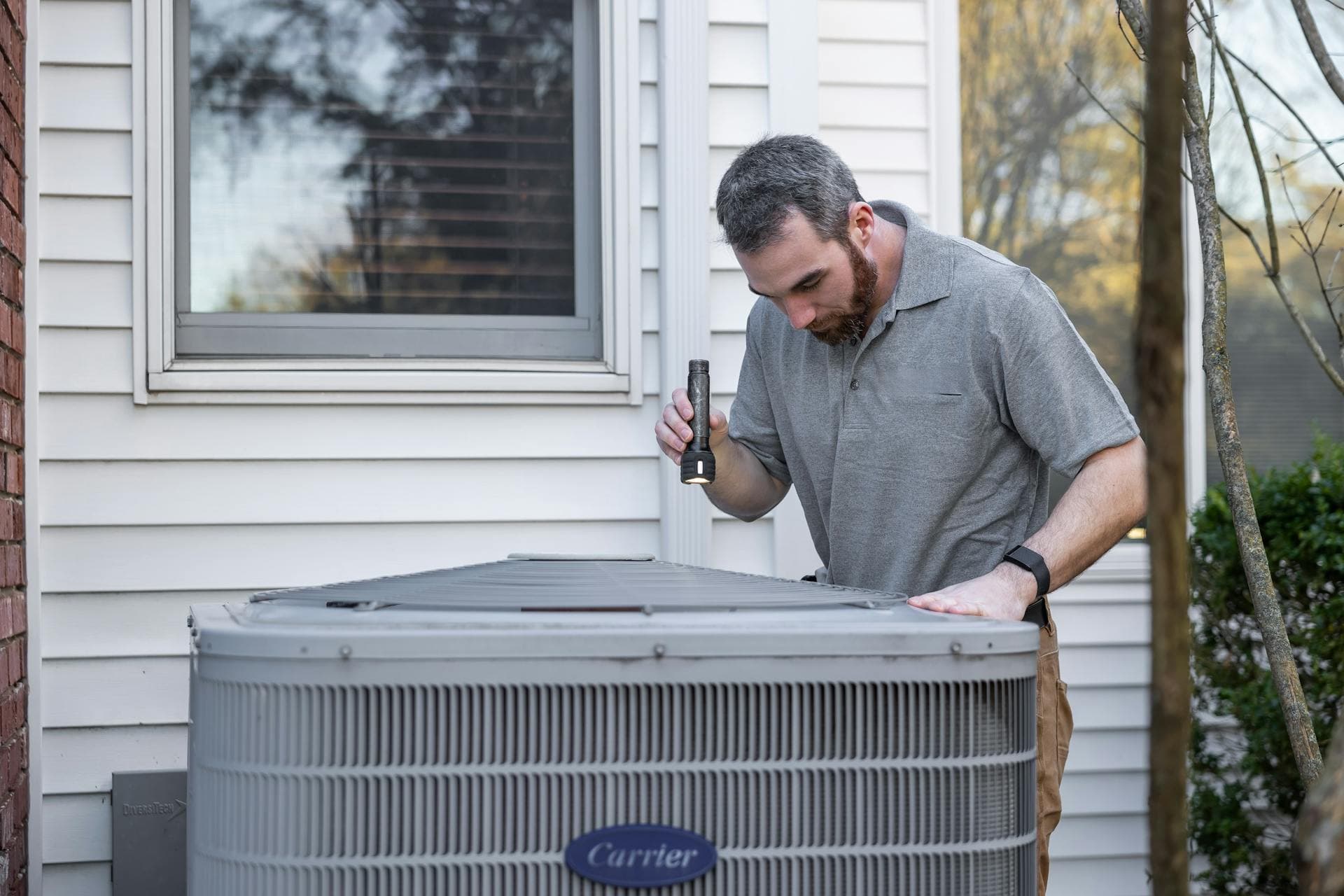 HVAC technician inspecting residential outdoor air conditioning unit