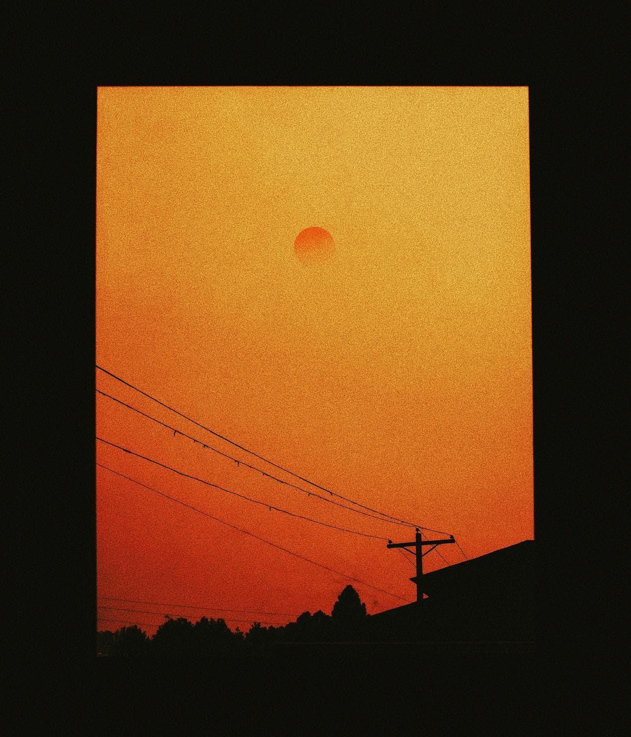 Orange sky from wildfire smoke haze with silhouetted power lines on West Coast