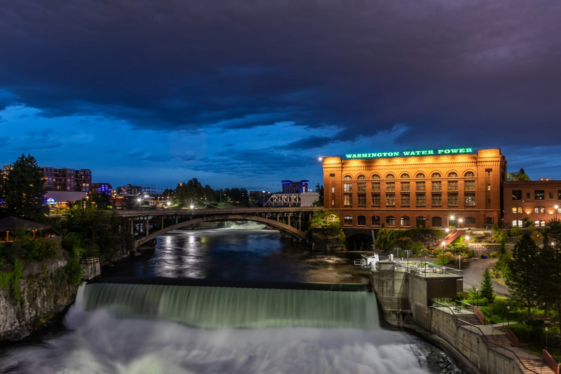 Spokane Falls at night with illuminated Washington Water Power building and city lights